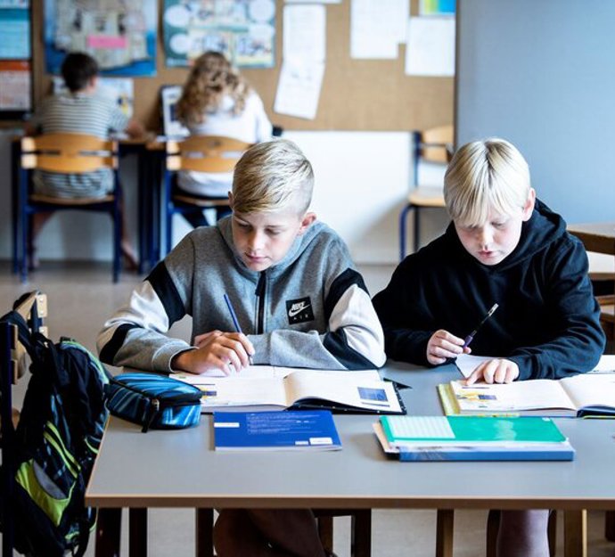 To elever sidder ved et bord i klasselokalet