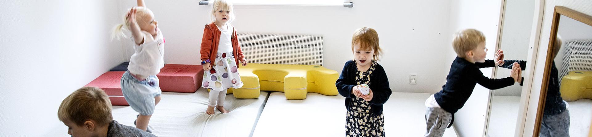 Foto af glade dagplejebørn som danser og hopper