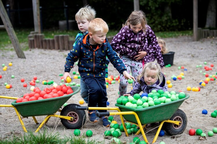 Fire børn på en legeplads leger med farvede bolde