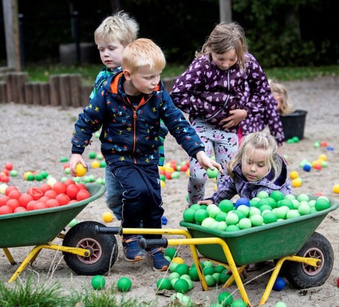 Fire børn på en legeplads leger med farvede bolde